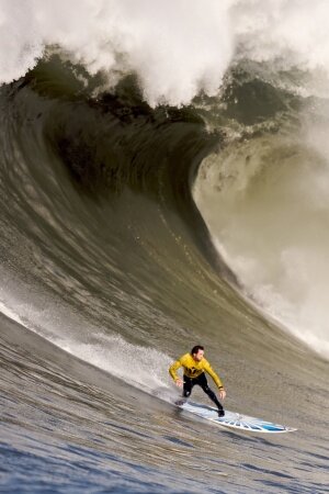 A Surfer Rides Down A Wave Mobile Wallpaper
